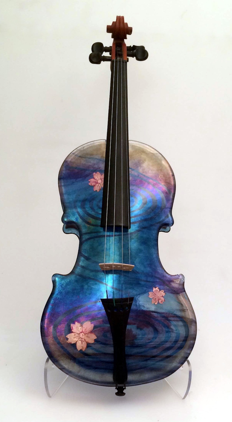Violin with glass front and back. The glass front features an iridescent swirling design with bring copper cherry blossomes